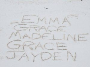 The names of the founders daughters carved in the sand on a beach