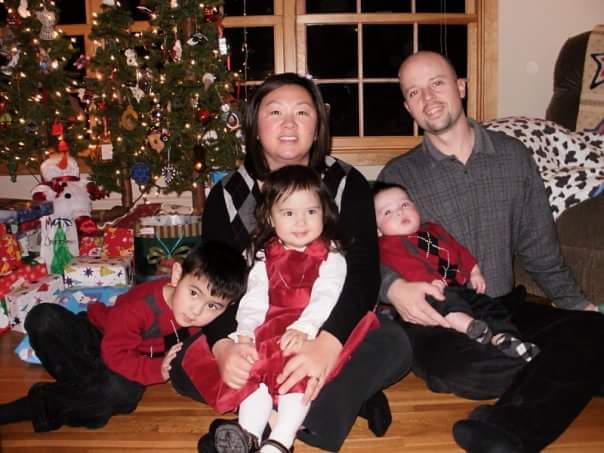 Mylynn Tufte sits in front of her Christmas tree with her three children and her husband