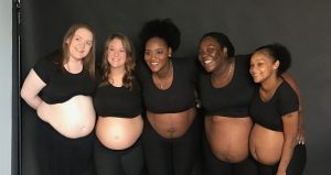A diverse group of expectant moms smile for a group photo