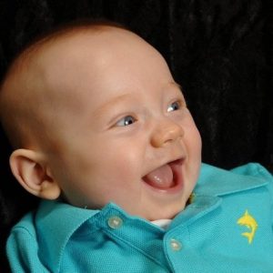 Baby Save Cooper smiles and wears a light blue polo shirt