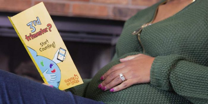 An expectant mom reads a Count the Kicks brochure.