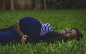 Pregnant Black woman lying on a green grassy field