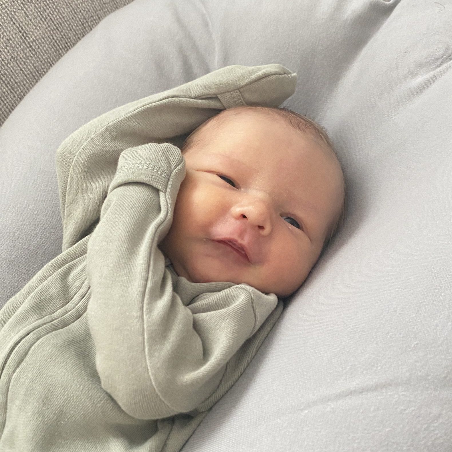 Newborn Jude wearing a gray sleeper