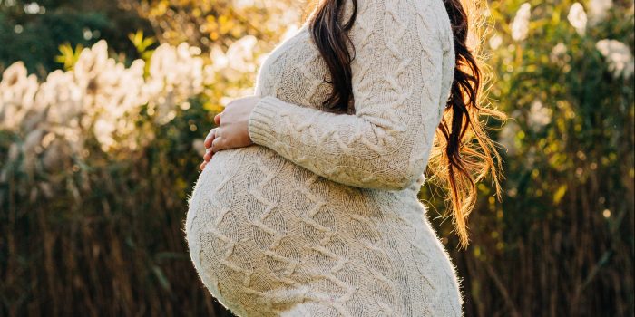 A pregnant mom rests her hands on her belly.