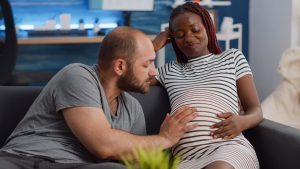 An expectant couple bonds while feeling their baby move in the mom's belly.