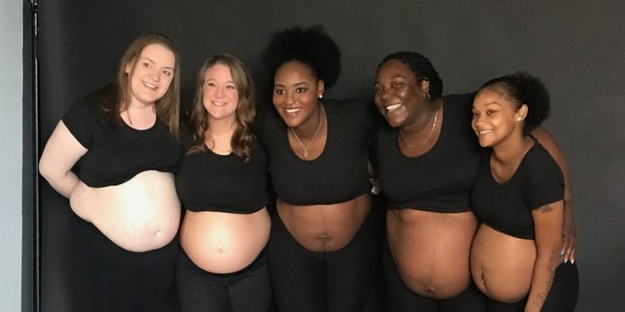 A diverse group of expectant moms smile for a group photo