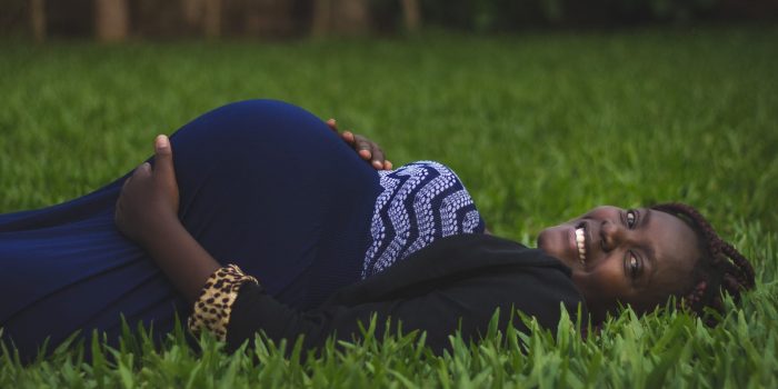 Pregnant Black woman lying on a green grassy field