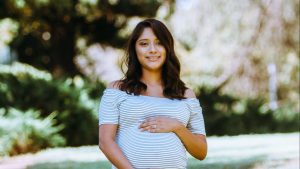 An expectant mom rests her hands on her baby bump.