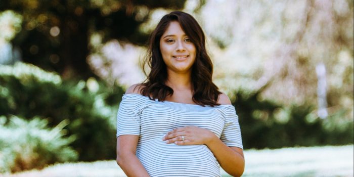 An expectant mom rests her hands on her baby bump.