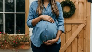 Pregnant woman holding hands on her belly.