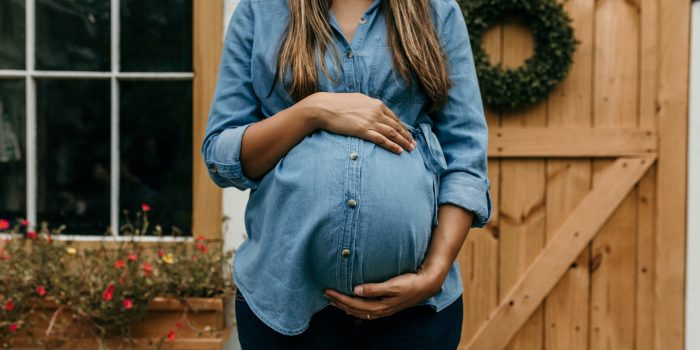 Pregnant woman holding hands on her belly.