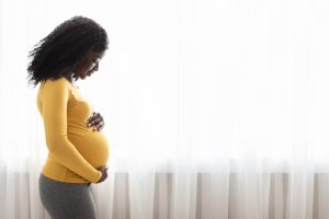 Pregnant woman looks down at her belly.