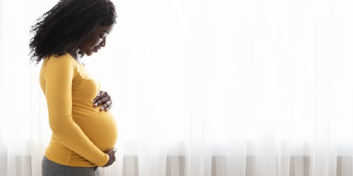 Pregnant woman looks down at her belly.