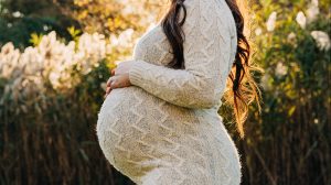 A pregnant mom rests her hands on her belly.