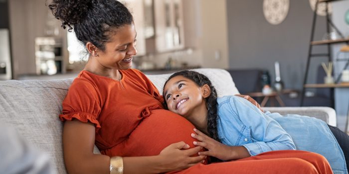 Daughter hugs belly of her pregnant mama.