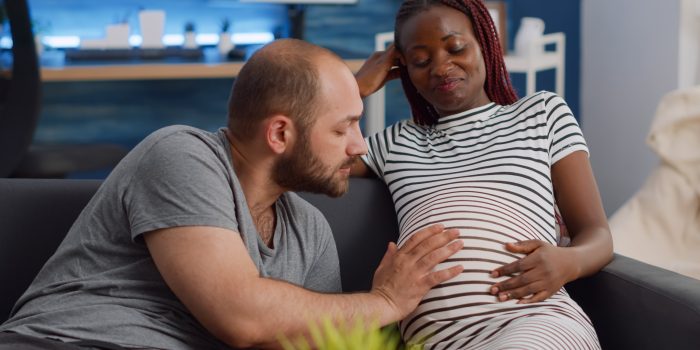 An expectant couple bonds while feeling their baby move in the mom's belly.