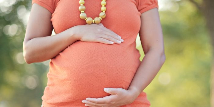 Pregnant woman resting her hands on her belly