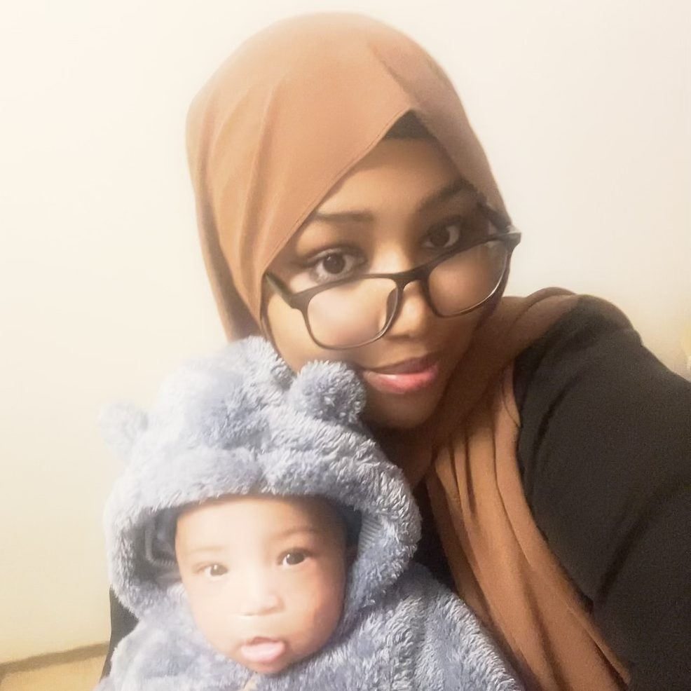 A woman with glasses and a hijab lovingly holds a baby