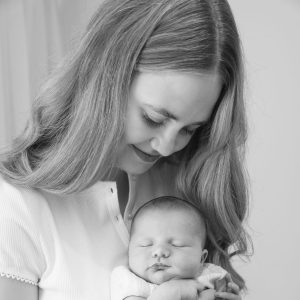Black-and-white photo of a woman gently holding a sleeping newborn baby in her arms.